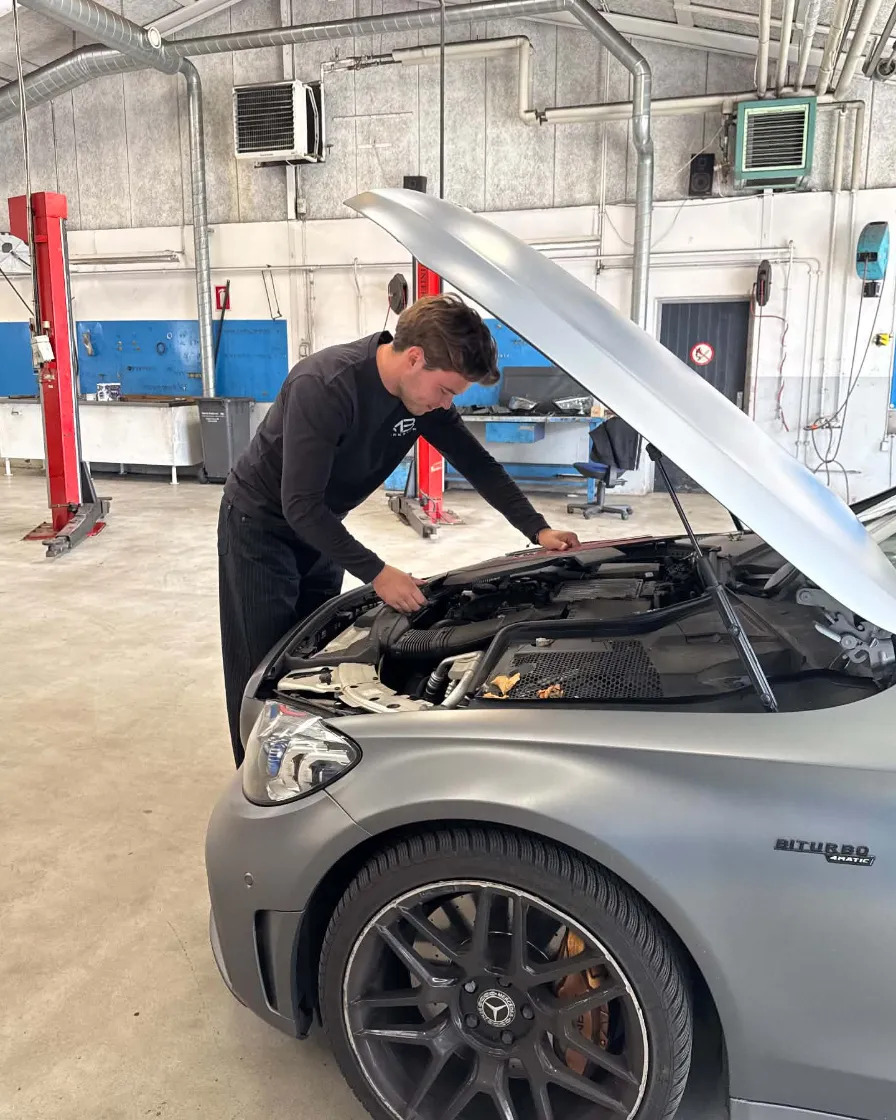 Mathias arbejder i motorrummet på en Mercedes i værkstedet